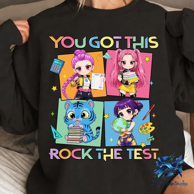 May include: Black sweatshirt with the text "YOU GOT THIS ROCK THE TEST" and colorful anime-style illustrations. The design includes images of students, a tiger, a calculator, books, and a globe.