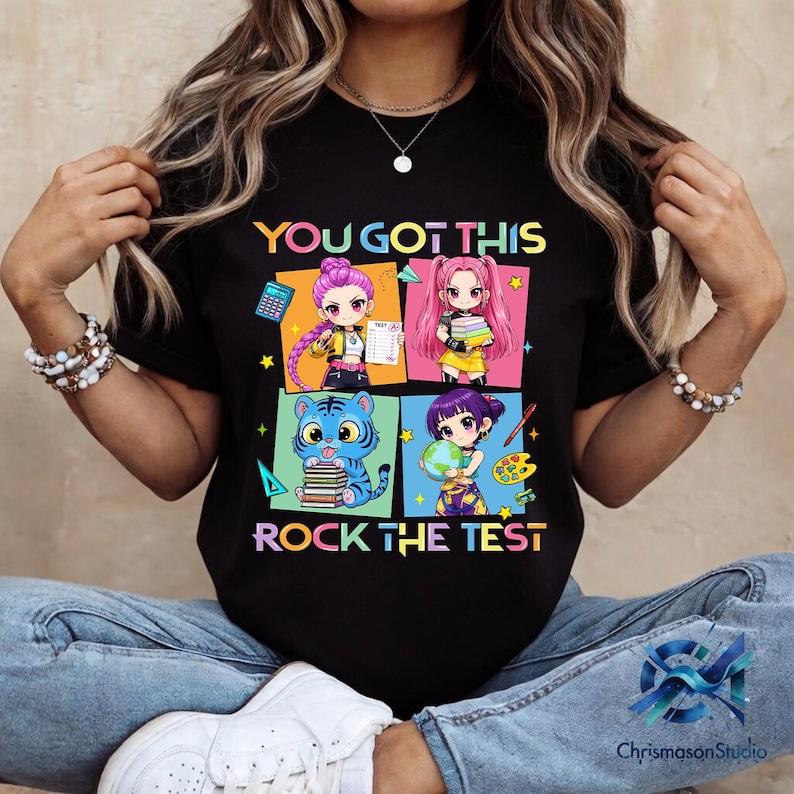 May include: Black t-shirt with the text "YOU GOT THIS ROCK THE TEST" and colorful anime-style illustrations. The illustrations feature four different characters with books, a calculator, and a globe.