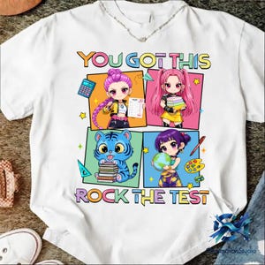 May include: White t-shirt with the text "YOU GOT THIS" and "ROCK THE TEST" in colorful block letters. The shirt features four anime-style illustrations of students with school supplies, including a calculator, books, and a globe.