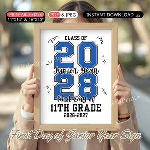 May include: A rectangular wooden frame containing a white sign with blue and black text that reads: CLASS OF 2028, Junior Year, FIRST DAY OF 11TH GRADE, 2026-2027. The sign features decorative doodle accents and is designed for 28x36 cm and 41x51 cm prints.