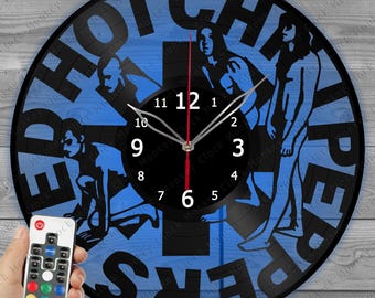 May include: Black vinyl record clock with a blue background and the words "HOT CHILI PEPPERS" cut out. The clock features a black clock face with white numbers and silver hands. A remote control is in the lower left corner.