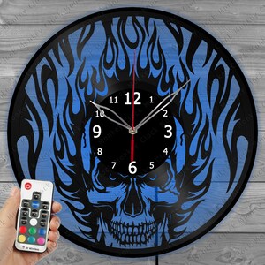 Könnte beinhalten: Eine schwarze Vinyl-Schallplattenuhr mit einem Design aus blauem Schädel und Flammen. Das Zifferblatt ist schwarz mit weißen Zahlen und silbernen Zeigern. Ein roter Sekundenzeiger bewegt sich über das Zifferblatt. Inklusive RF Wireless Fernbedienung.