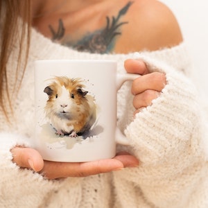 May include: White ceramic mug with a watercolor illustration of a brown and white guinea pig. The guinea pig is looking at the camera.