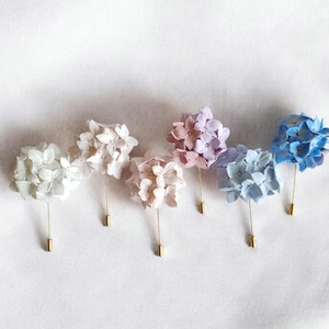 May include: Five hydrangea flower pins in shades of white, pink, and blue. The pins are arranged in a row on a white background.
