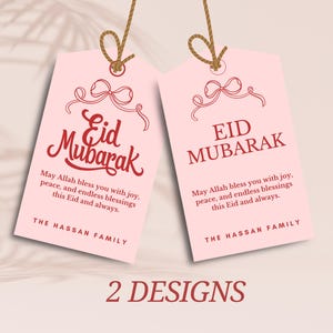 Puede incluir: Dos etiquetas de regalo rosas con texto rojo y un diseño de lazo rojo. El texto en las etiquetas dice "Eid Mubarak" y "Que Allah te bendiga con alegría, paz y bendiciones infinitas en este Eid y siempre." Las etiquetas están etiquetadas "The Hassan Family".