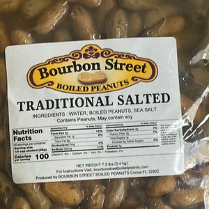 May include: A bag of Bourbon Street Boiled Peanuts, Traditional Salted, with a net weight of 7.5 lbs (3.4 kg). The bag is clear plastic and shows the peanuts inside. The label is white with black text and a yellow logo. The label includes the ingredients: water, boiled peanuts, sea salt. It also states that the product contains peanuts and may contain soy. The nutrition facts are listed on the label.