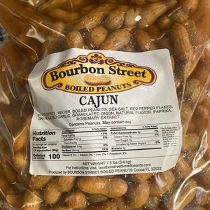 May include: A bag of Cajun boiled peanuts from Bourbon Street Boiled Peanuts. The bag is filled with peanuts in a clear, brown liquid. The label includes the ingredients, nutrition facts, and net weight of 7.5 lbs (3.4 kg).