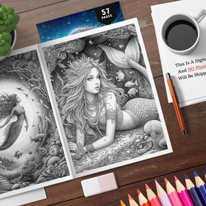 Puede incluir: Un libro para colorear en escala de grises abierto en dos p&aacute;ginas con ilustraciones de sirenas. Una sirena nada, la otra est&aacute; reclinada. El libro est&aacute; sobre una superficie de madera con l&aacute;pices de colores, una taza de caf&eacute; y una planta. El texto en un papel dice: "This Is A Digital Product, And NO Physical Item Will Be Shipped To You."