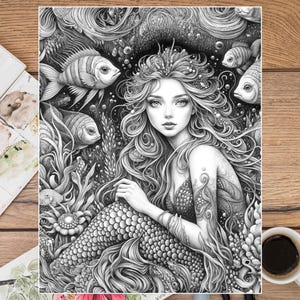 Puede incluir: Ilustraci&oacute;n en blanco y negro de una sirena con largo cabello suelto, una corona y una cola escamosa, rodeada de peces y plantas acu&aacute;ticas. La obra de arte es detallada e intrincada, con un enfoque en el rostro de la sirena y el entorno submarino.