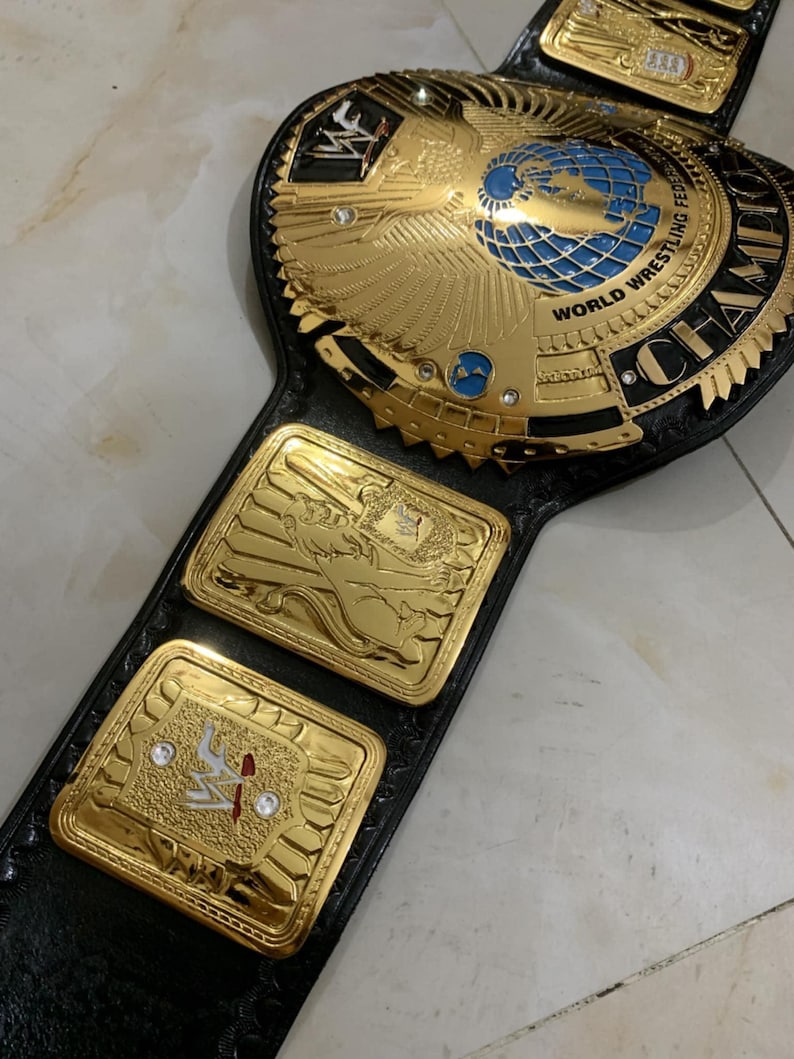May include: A gold and black wrestling championship belt with a large eagle and globe design in the center. The belt has the words "World Wrestling Federation" and "Champion" on it.