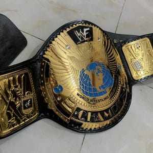 May include: A gold and black wrestling championship belt with a blue globe and the words "World Wrestling Federation Champion" on the front.