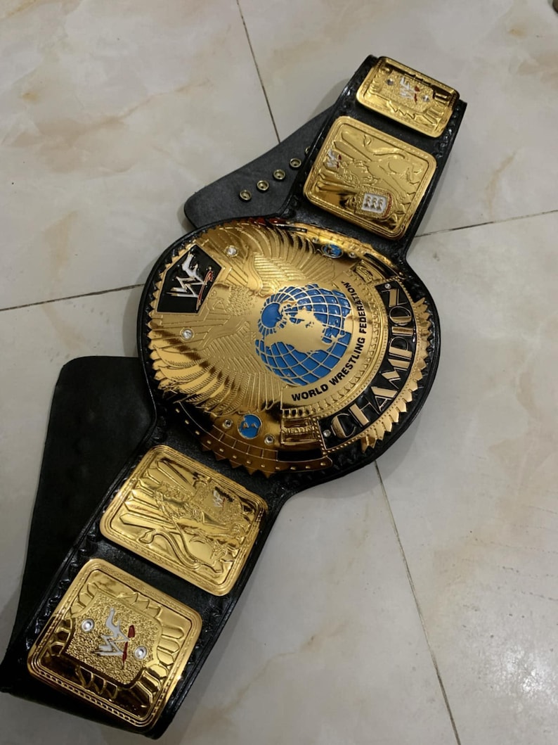 May include: A gold and black wrestling championship belt with a large center plate featuring a globe and the words "World Wrestling Federation" and "Champion".