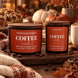 Puede incluir: Dos velas cilíndricas negras de cera de soja con tapas de madera oscura y etiquetas color óxido. La vela más grande indica 15 oz y la más pequeña 8 oz. Ambas presentan el texto TWOFOLDCONTENT COFFEE cake SOY WAX CANDLE.