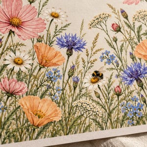 Close-up of the print’s floral details on textured ivory paper, showing peach poppies, pink cosmos, purple cornflowers, blue forget-me-nots, and a small bumblebee resting on a white daisy.