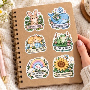 Decorated notebook
Kraft spiral notebook decorated with pastel bunny, whale, kitten, frog, rainbow, and sunflower faith stickers, beside a pink pen, daisies, and coffee.