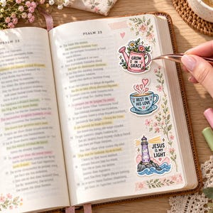 Bible journaling
Open Bible decorated with pastel Christian stickers featuring a watering can, teacup, and lighthouse. A hand places the “Grow in Grace” sticker with tweezers.