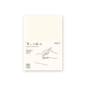 Pode incluir: Caderno MD creme com texto japonês e um desenho a traço de uma mão a escrever com uma caneta. O caderno tem o texto "Designed for Comfortable Writing" e "MD Paper" impresso na capa.
