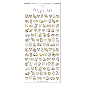 Peut inclure: Une planche d'autocollants Tiny Tiny avec des illustrations de renards de dessins animés en jaune, orange, gris et lavande. Les autocollants sont sur fond blanc avec le texte "RELAXED AND COMFORTING" et "TINY TINY" en haut, et "WE ARE KITSUNE" en bas.