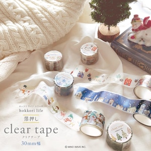 Könnte beinhalten: Mehrere Rollen transparentes Klebeband mit winterlichen Motiven, darunter Schneemänner, Schneeflocken und Häuser. Das Klebeband ist 30 mm breit und trägt den Schriftzug "clear tape" sowie japanischen Text. Der Hintergrund zeigt eine weiße Strickdecke.