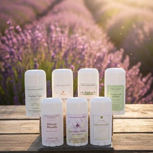 May include: Seven white cylindrical deodorant sticks with labels reading Herbal Spa, Spice, Woodland, Fresh and Herbal, Floral Woods, Lavender Fields, and Deodorant. Each container displays net weight information in grams, arranged on a wooden surface.