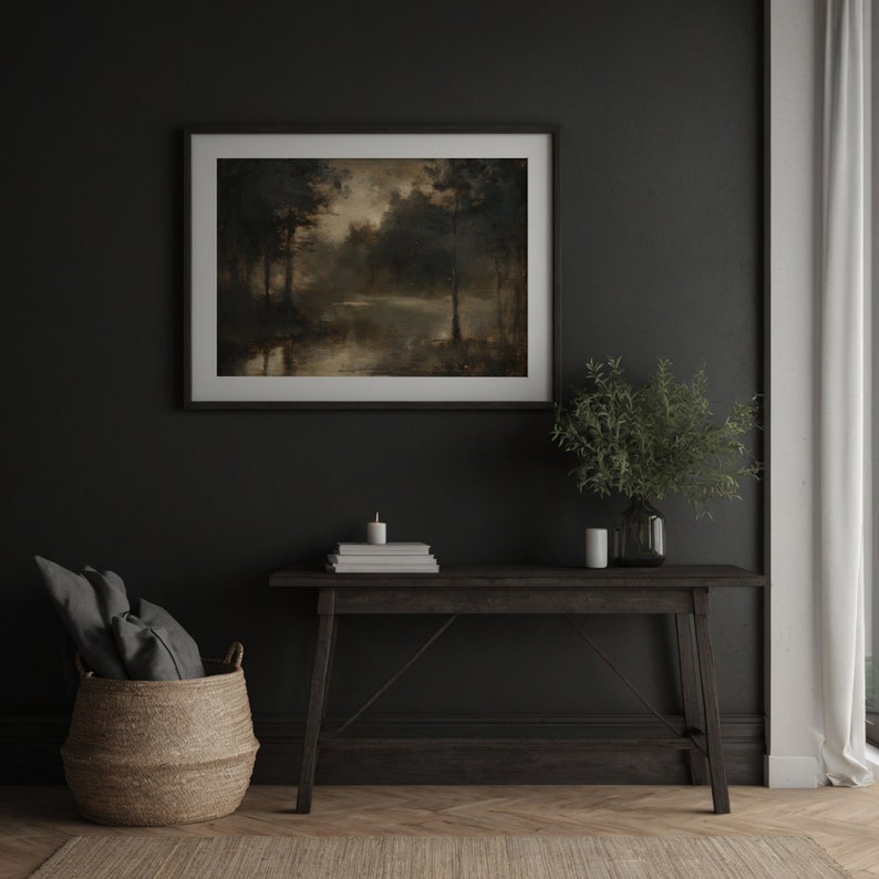 Op de afbeelding: Een donkerhouten consoletafel met een ingelijst landschapschilderij erboven. Het schilderij toont een boslandschap met een meer op de voorgrond. Een kleine plant in een pot en een stapel boeken staan op de tafel.
