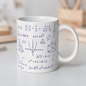 May include: A white ceramic mug featuring a dark blue print of various mathematical equations, algebraic formulas, geometric shapes, and trigonometric functions including sine waves, parabolas, and right triangles scattered across the exterior surface.