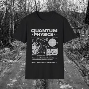 May include: A black short-sleeve t-shirt featuring a white graphic print that includes the text "QUANTUM PHYSICS", "EXPLORE THE COSMOS", and "UNLOCK THE SECRETS OF THE UNIVERSE", along with Euler's identity, a human head silhouette, and a wave graph.