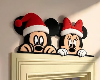 May include: A decorative door topper featuring Mickey and Minnie Mouse characters wearing red and white Santa hats. The black, white, red, and tan figures are positioned as if peeking over the top edge of a light-colored door frame.