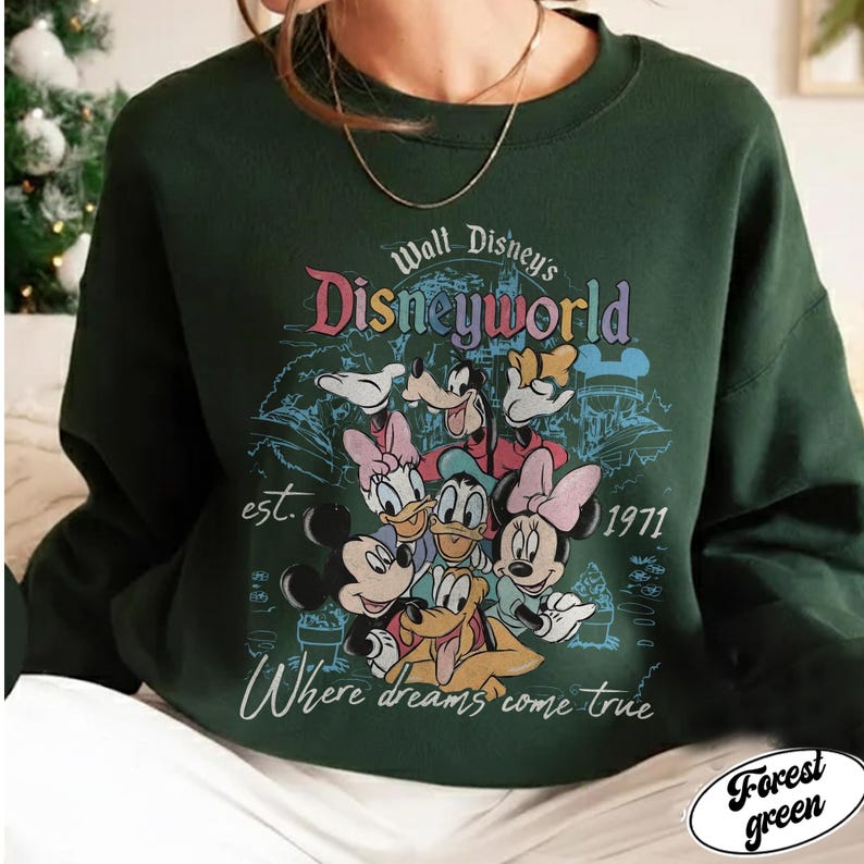 May include: Forest green sweatshirt featuring a colorful graphic of Disney characters, including Mickey Mouse, Minnie Mouse, Donald Duck, and Goofy. The design includes the text "Walt Disney's Disneyworld" and "Where dreams come true", with the year "1971".