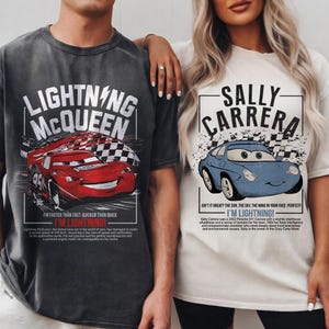 May include: Two t-shirts featuring characters from the movie Cars. One is dark gray with Lightning McQueen and the text "I'M LIGHTNING!". The other is off-white with Sally Carrera and the text "I'M LIGHTNING!".