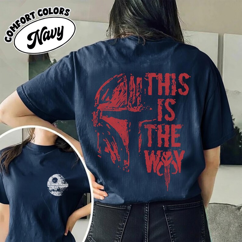 May include: Navy blue t-shirt featuring a red graphic of a helmet and the text "THIS IS THE WAY". The shirt also has a smaller graphic of the Death Star on the front. The shirt is made of a soft, comfortable material.
