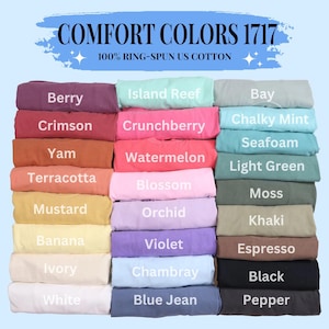 Puede incluir: Una pila de 18 camisetas dobladas en varios colores, incluyendo bayas, carmes&iacute;, &ntilde;ame, terracota, mostaza, pl&aacute;tano, marfil, blanco, arrecife de isla, grosella, sand&iacute;a, flor, orqu&iacute;dea, violeta, chambray, mezclilla azul, bah&iacute;a, menta calc&aacute;rea, espuma de mar, verde claro, musgo, caqui, espresso, negro y pimienta. El texto "COMFORT COLORS 1717" y "100% RING-SPUN US COTTON" est&aacute; en la parte superior de la imagen.