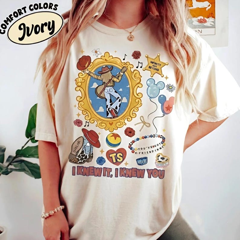 Puede incluir: Una camiseta de color marfil con un estampado gr&aacute;fico que presenta un marco dorado ornamentado central con una figura con guitarra, rodeada de iconos que incluyen una estrella con texto, globos, una bota de vaquero, una pelota y el texto I KNEW IT, I KNEW YOU.