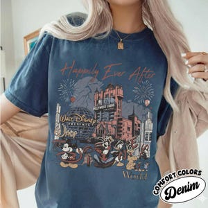 Puede incluir: Camiseta azul marino con un gr&aacute;fico que presenta personajes de Disney y el texto "Happily Ever After". El dise&ntilde;o incluye el Hollywood Tower Hotel, fuegos artificiales y las palabras "Walt Disney World". La camiseta tambi&eacute;n tiene las palabras "Comfort Colors Denim".