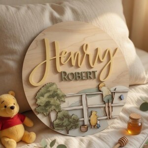 May include: A circular wooden wall sign featuring the name Henry Robert in raised yellow and green lettering. The design includes a layered illustration of a person and a bear standing by a wooden fence near trees, with a small blue butterfly.