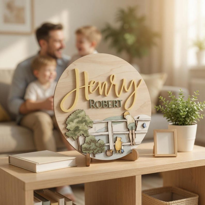 May include: A circular wooden sign featuring the name Henry in large yellow script and Robert in smaller dark green text. The base displays a layered scene with trees, a white fence, a small honey pot, and figures of a bear and a small animal.