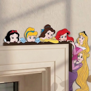May include: A decorative wooden shelf featuring cartoon images of Disney princesses, including Snow White, Cinderella, Belle, Ariel, Aurora, and Rapunzel. The princesses are depicted with their signature hairstyles and outfits, peeking over the shelf.