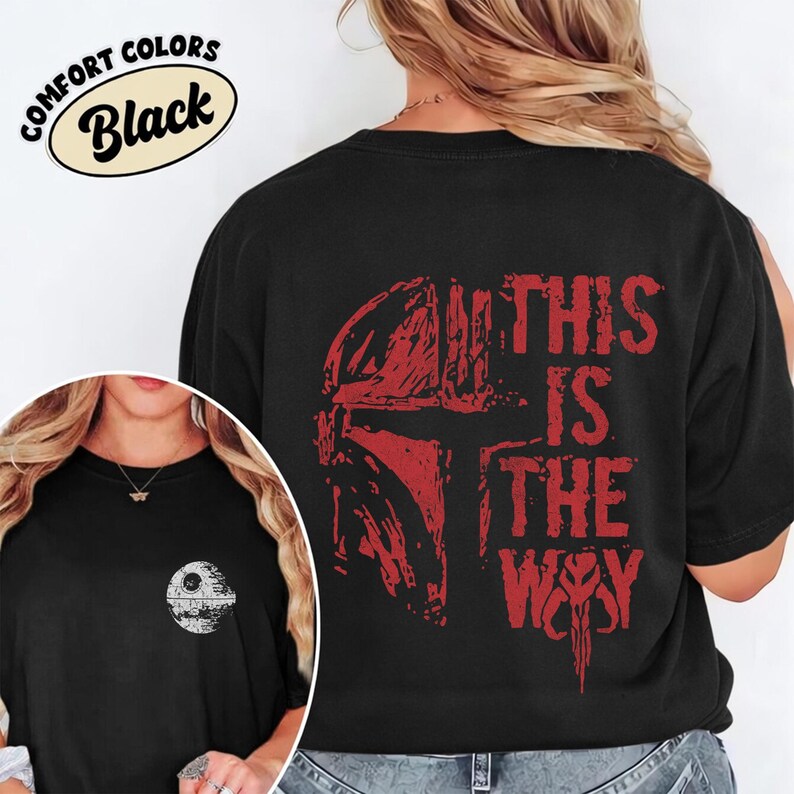 May include: Black t-shirt with a red graphic of a Mandalorian helmet and the text "THIS IS THE WAY." The shirt also features a small Death Star graphic on the front. The words "COMFORT COLORS" and "Black" are in a circular design.
