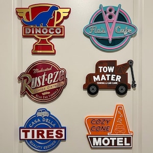 Può includere: Sei insegne decorative da parete con loghi e immagini iconiche della serie di film Cars, tra cui Dinoco, Flo's V8 Cafe, Rust-eze, Tow Mater Towing & Car Care, Casa Della Tires e il Cozy Cone Motel, realizzate in colori vivaci.
