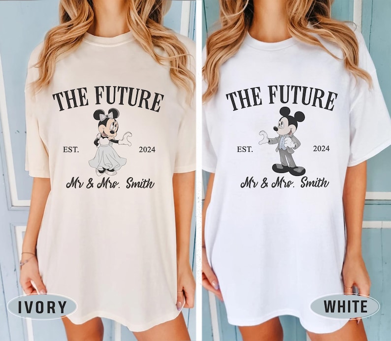 Puede incluir: Dos camisetas blancas con un estampado gr&aacute;fico negro de Mickey y Minnie Mouse. El texto en las camisetas dice "The Future" con el a&ntilde;o "2024" y "Est.". El texto tambi&eacute;n dice "Mr. & Mrs. Smith". Las camisetas se muestran en dos modelos, uno con una camiseta de color marfil y el otro con una camiseta blanca.