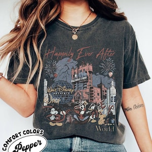 Puede incluir: Camiseta gris oscuro con un gr&aacute;fico desgastado que presenta el texto "Happily Ever After" y un dise&ntilde;o de Walt Disney World. El dise&ntilde;o incluye fuegos artificiales, el Hollywood Tower Hotel y personajes de Disney.