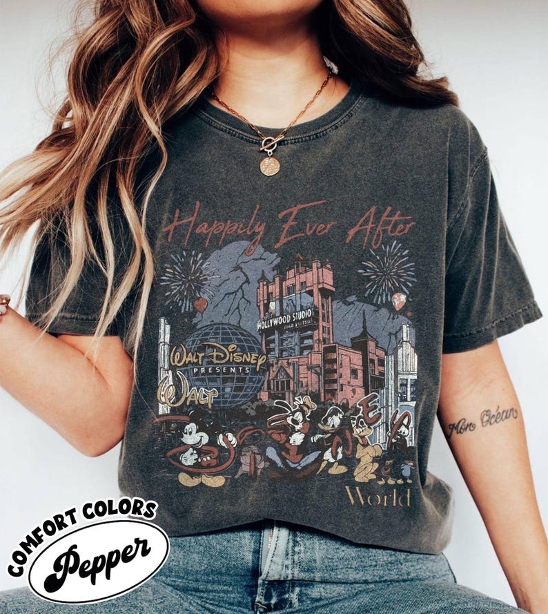 Puede incluir: Camiseta gris oscuro con un gr&aacute;fico desgastado que presenta el texto "Happily Ever After" y un dise&ntilde;o de Walt Disney World. El dise&ntilde;o incluye fuegos artificiales, el Hollywood Tower Hotel y personajes de Disney.