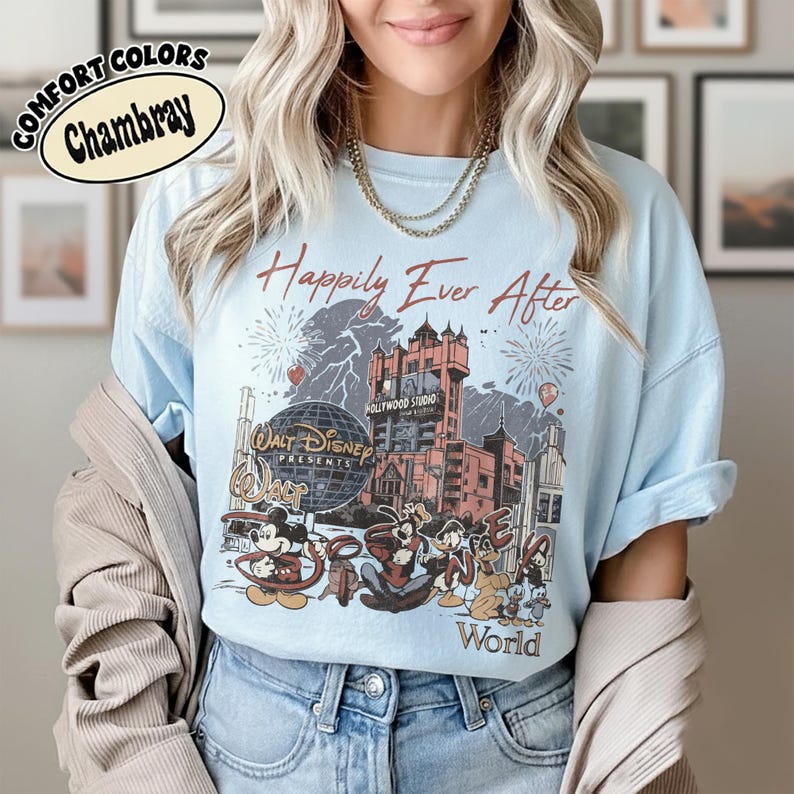Puede incluir: Camiseta azul claro Comfort Colors Chambray con un dise&ntilde;o de Disney. El dise&ntilde;o incluye el texto "Happily Ever After", fuegos artificiales, un castillo y personajes de Disney. Tambi&eacute;n se ven las palabras "Walt Disney World Presents".