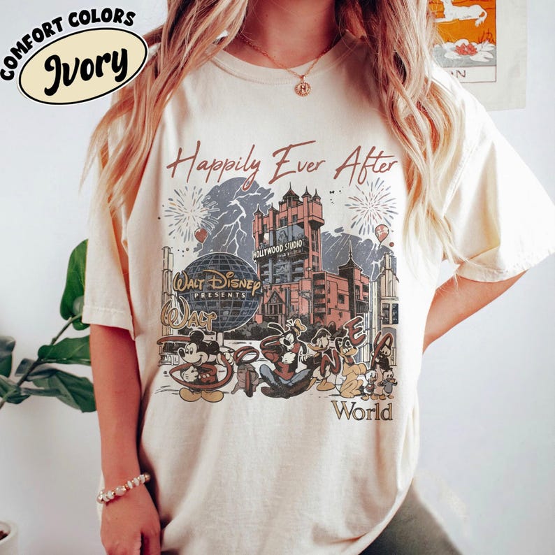 Puede incluir: Camiseta color marfil con un gr&aacute;fico que presenta a Mickey Mouse y sus amigos, el Hollywood Tower Hotel, y las palabras "Happily Ever After" y "Walt Disney World". La camiseta tiene un dise&ntilde;o vintage.