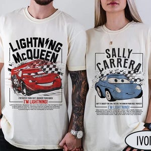 May include: Ivory-colored t-shirts featuring Lightning McQueen and Sally Carrera from the Cars movie. The Lightning McQueen shirt has a red race car graphic and text. The Sally Carrera shirt has a blue car graphic and text.