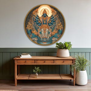 May include: A round wall art piece featuring a detailed illustration of a deity with multiple arms, in shades of blue, gold, and white. The artwork is set against a dark background and framed with a gold border. The piece is displayed above a wooden console table.