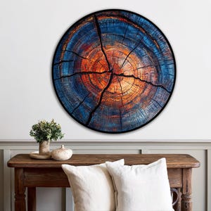 May include: A round wall art piece featuring a detailed cross-section of a tree trunk. The artwork showcases concentric rings in shades of blue, orange, and brown, with prominent cracks. The piece is framed with a black border, creating a striking visual.
