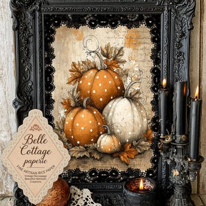 May include: A rectangular black ornate frame containing a print of three pumpkins with white polka dots surrounded by autumn leaves and script text. A diamond-shaped label reads Belle Cottage paperie Fine Artisan Rice Paper. Black candles are nearby.