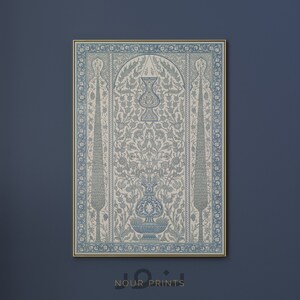K&ouml;nnte beinhalten: Ein blauer und wei&szlig;er gerahmter Druck mit einem komplizierten floralen Design und einer Vase in der Mitte. Der Druck hat einen goldenen Rahmen und den Text "Nour Prints" unten.