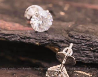 May include: A pair of silver stud earrings with a round, clear, sparkling stone in the centre of each earring.